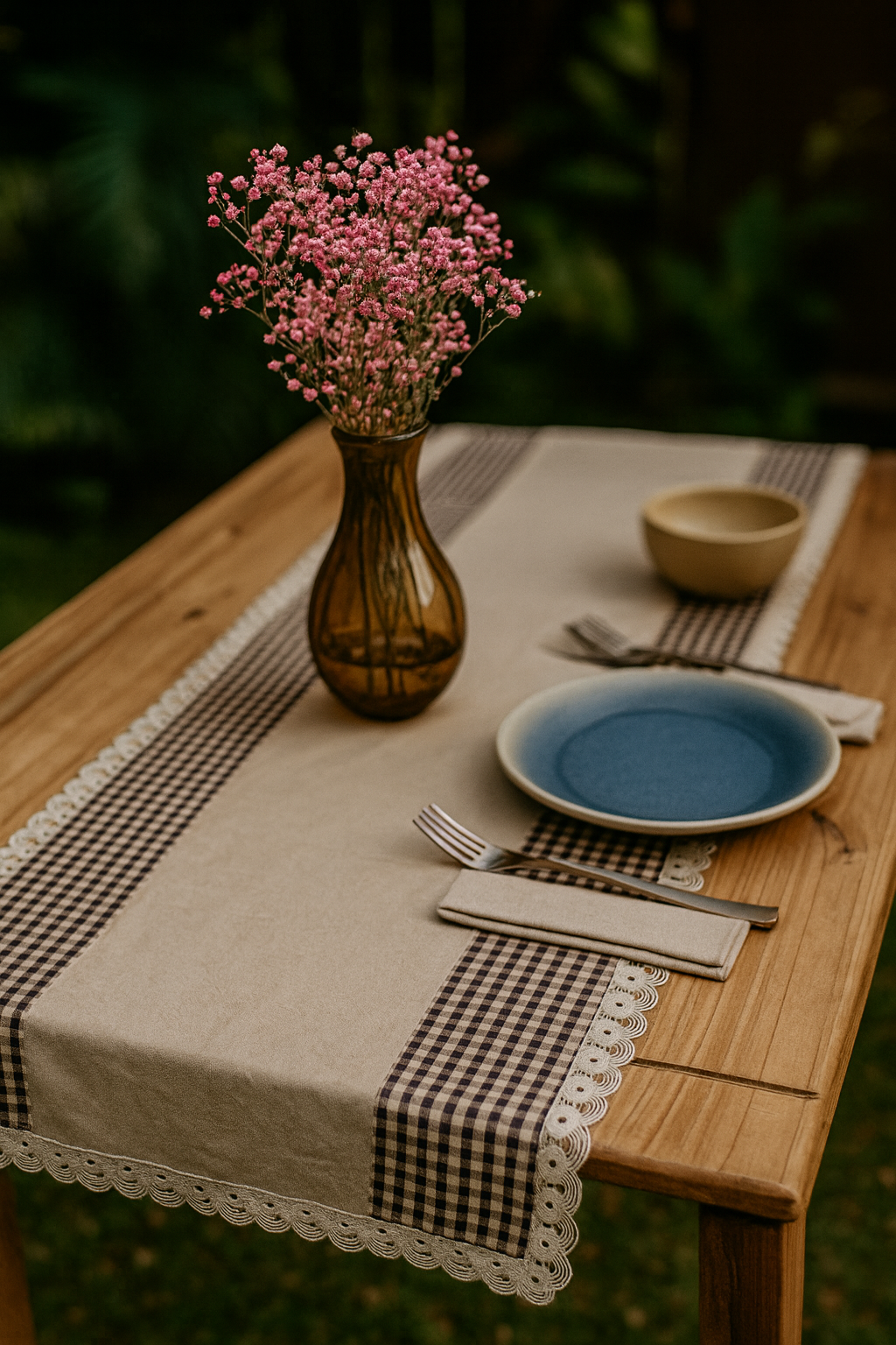 Table setting with a vase of pink flowers, plates, and cutlery on a wooden table. Rustic handmade table linen for cottage-style home décor