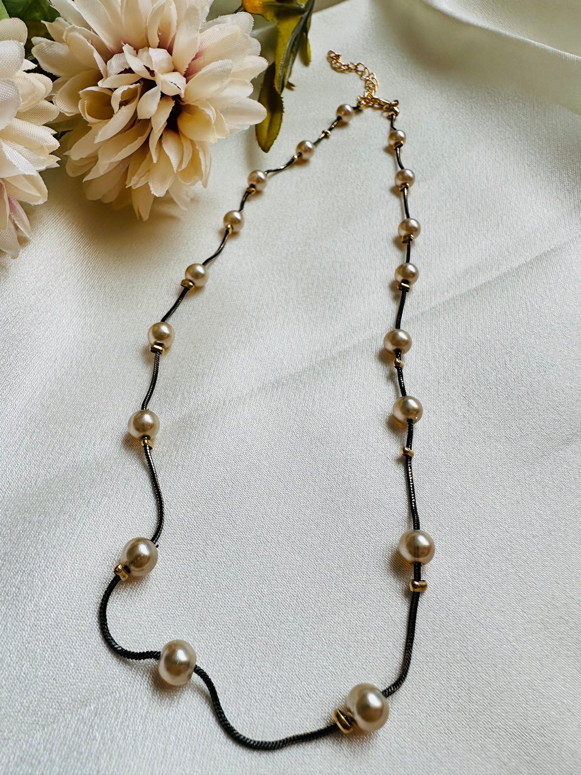 Black coloured chain Necklace with Beige coloured Pearl (Faux)  placed at equidistance. Elegant Statement Jewellery with adjustable hook and chain.