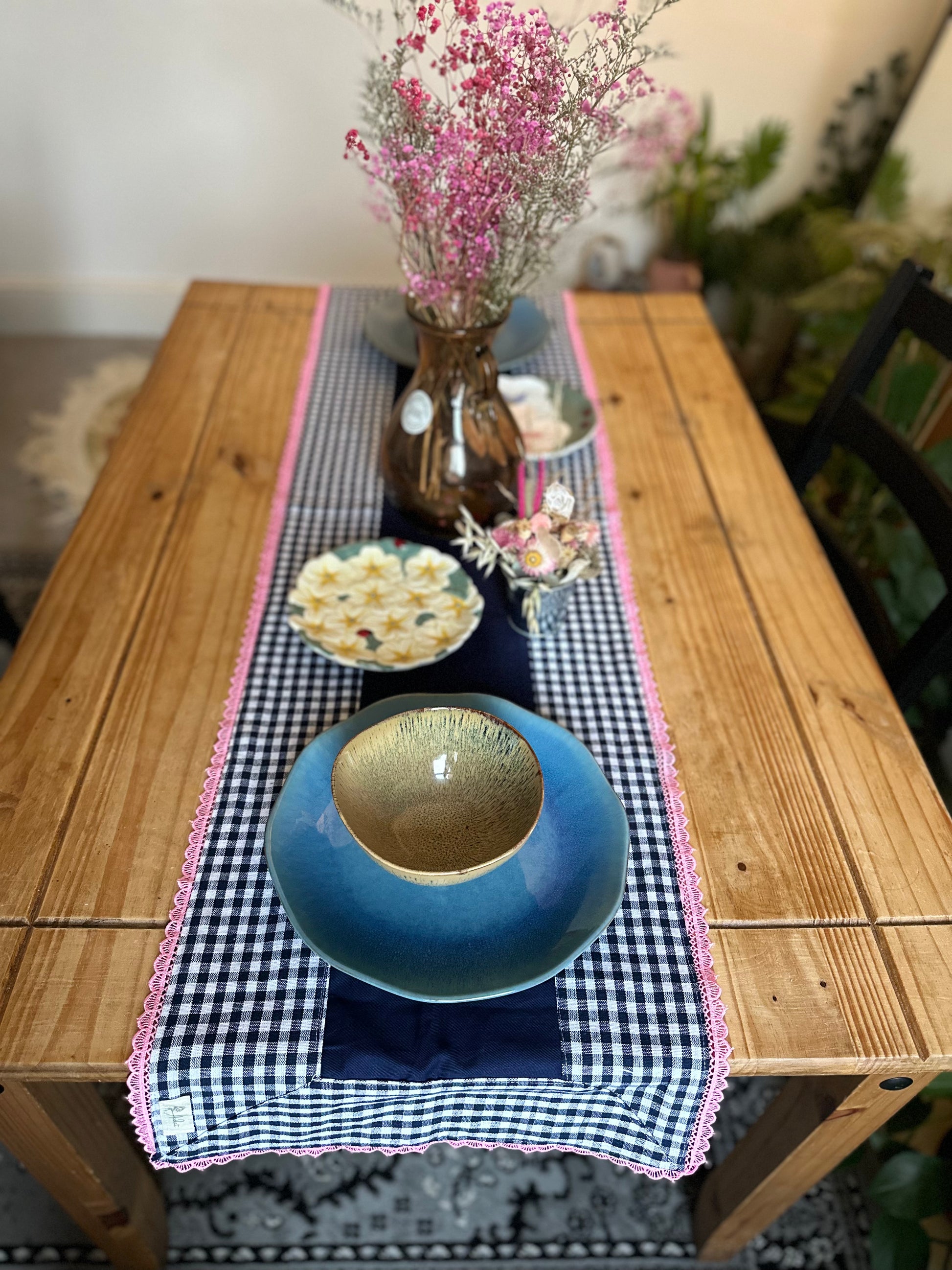Table setting with a blue bowl, checkered tablecloth, and decorative elements on a wooden table.