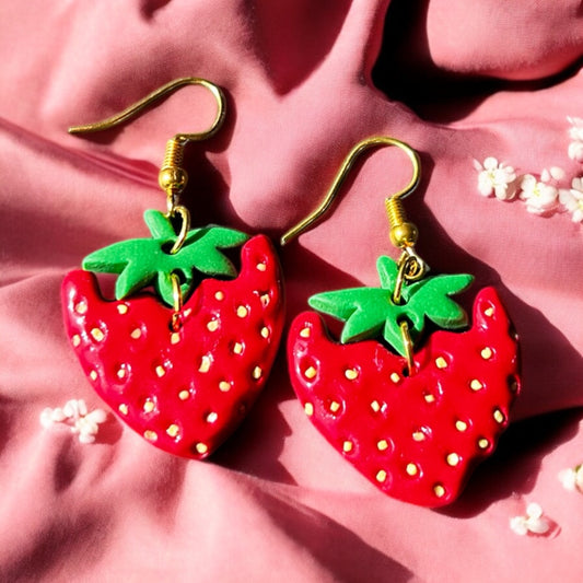 Close-up of handmade strawberry dangle earrings with green leaf tops