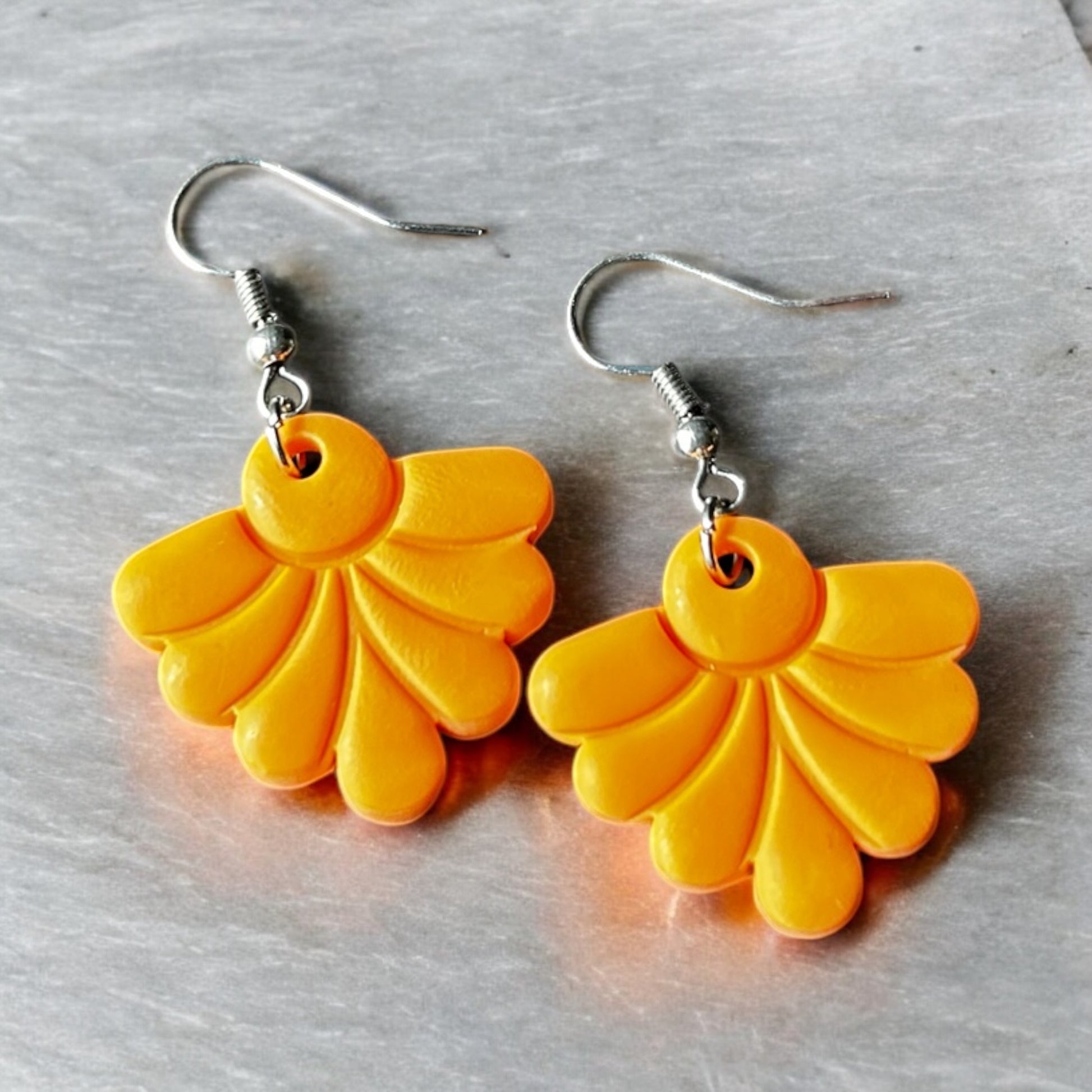 Lightweight orange dangle earrings on display
