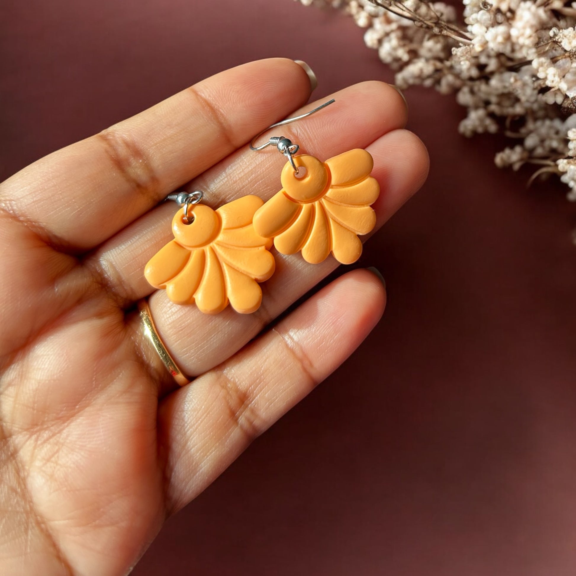 Close-up of handmade orange colour dangle earrings 
