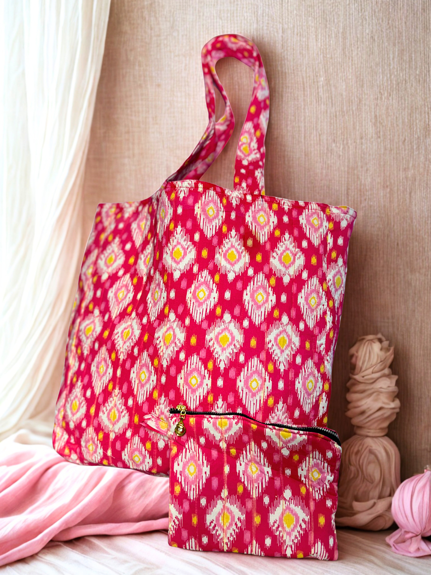 A pink patterned tote bag with a matching zippered pouch resting over a plain wall. white curtain 