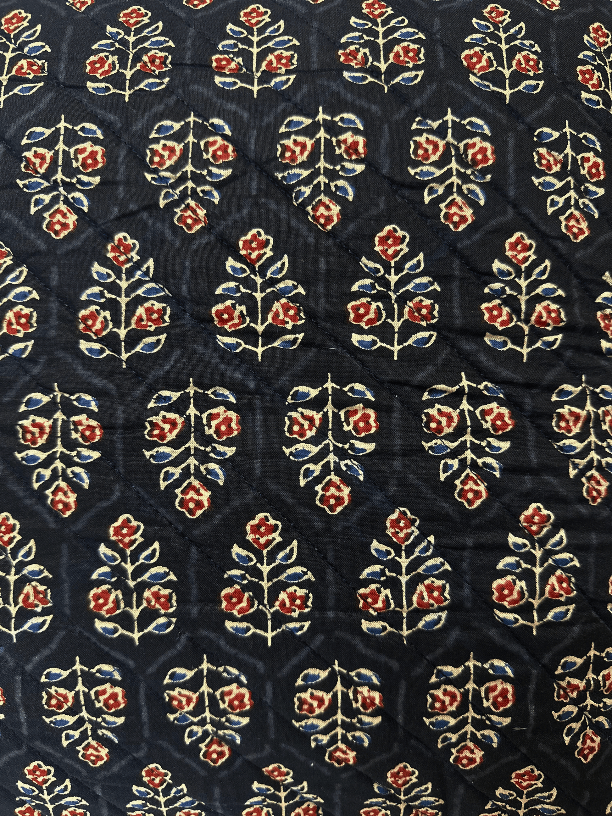 quilted block print cushion fabric with floral design on a dark background