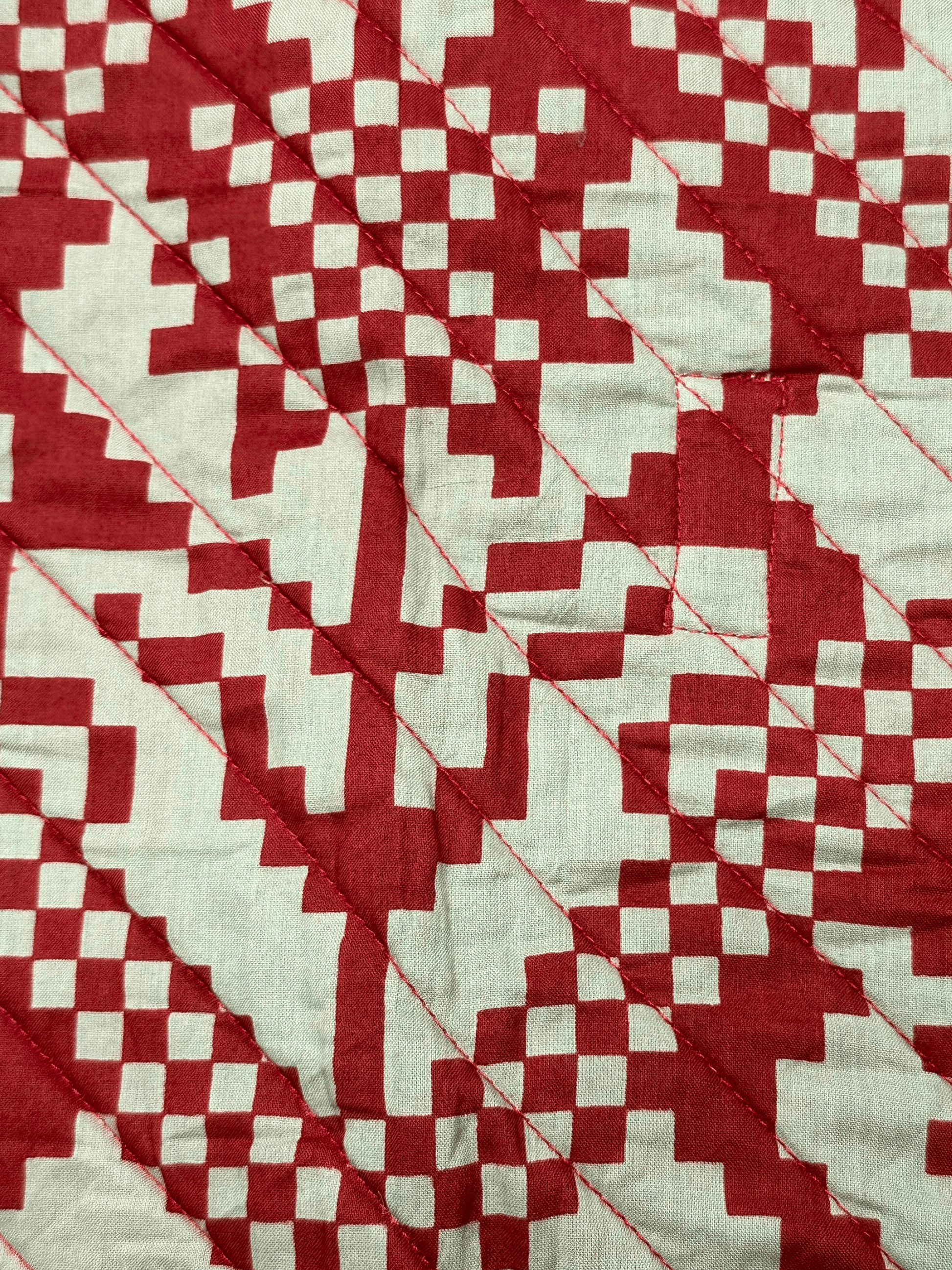 Maroon and white quilted cushion with geometric pattern