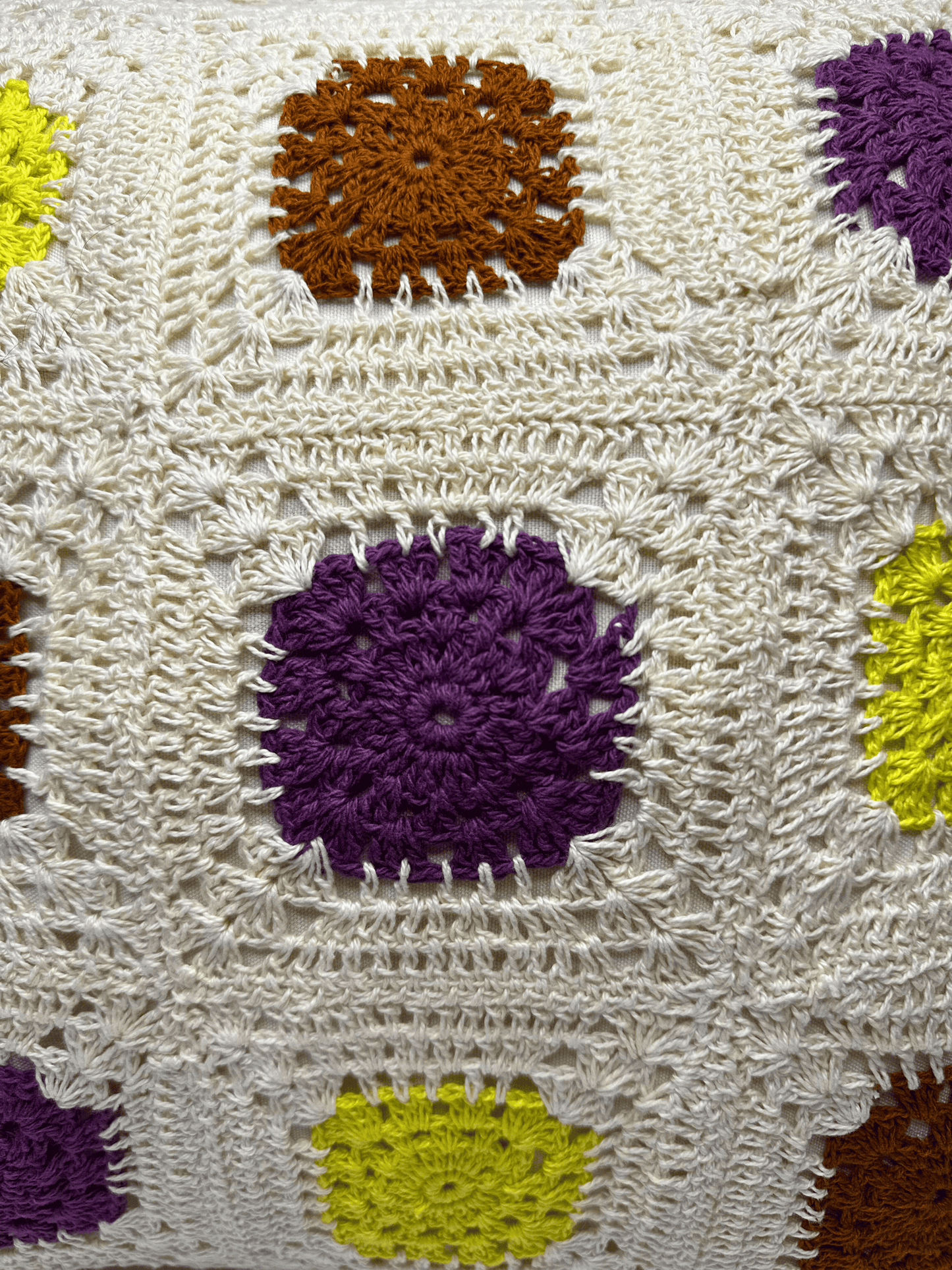 Close-up of a crocheted cushion cover with colourful flower patterns.