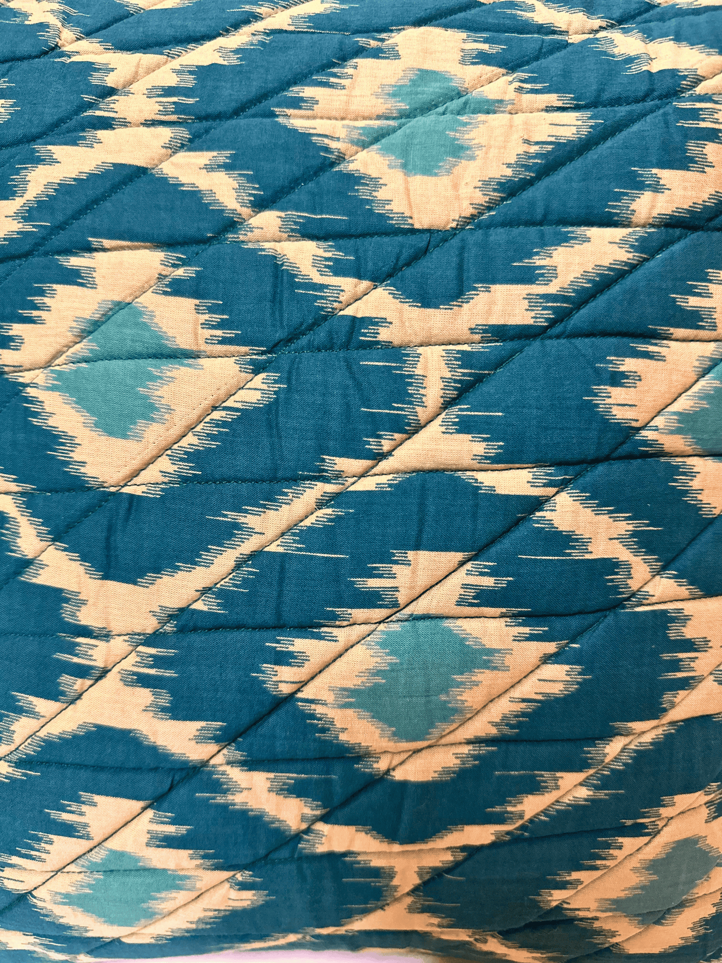 Blue and beige patterned quilted cushion fabric with diamond shapes