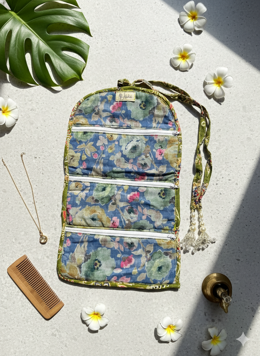 Floral jewellery organiser opened into 3 sections with zippers on a light surface with flowers and a comb.