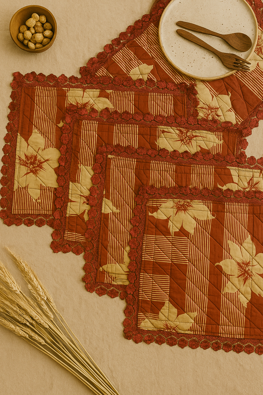 Set of floral-patterned placemats with lace borders on a beige surface with a small bowl and cutlery.
